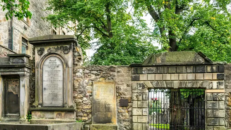 Guide leading a group through Greyfriars Kirkyard on an Edinburgh ghost tour of the haunted vaults and graveyard, Old Town, Scotland
