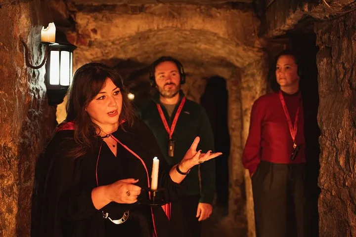 Storyteller guide with a small group at the Mercat Cross on an Edinburgh ghost tour of the Blair Street vaults, Royal Mile, Scotland