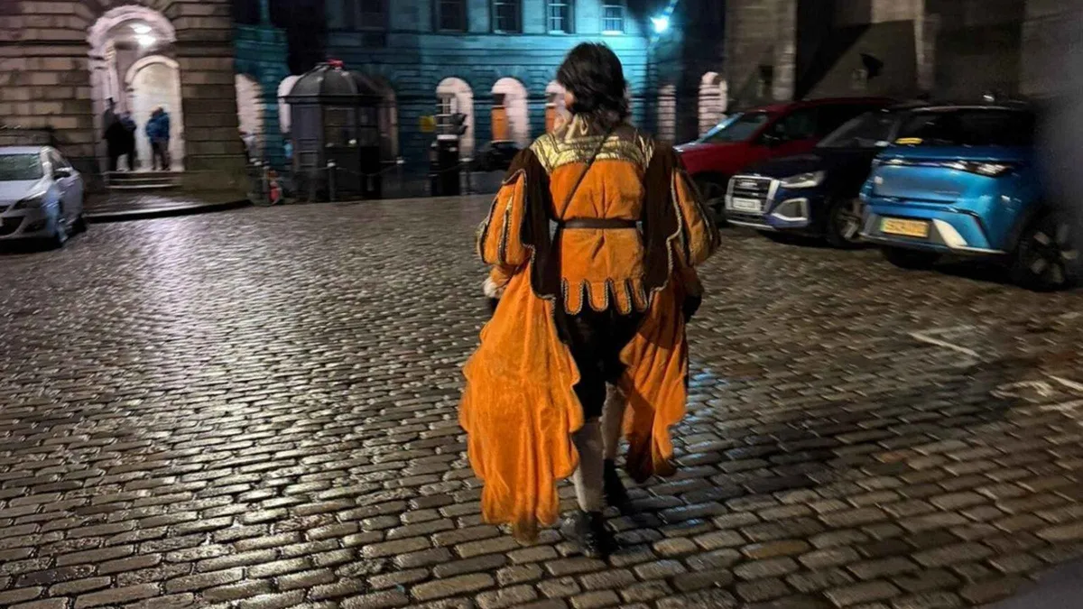 Guide with a group in a Royal Mile close on an Edinburgh ghost tour toward the underground vaults, Old Town, Scotland